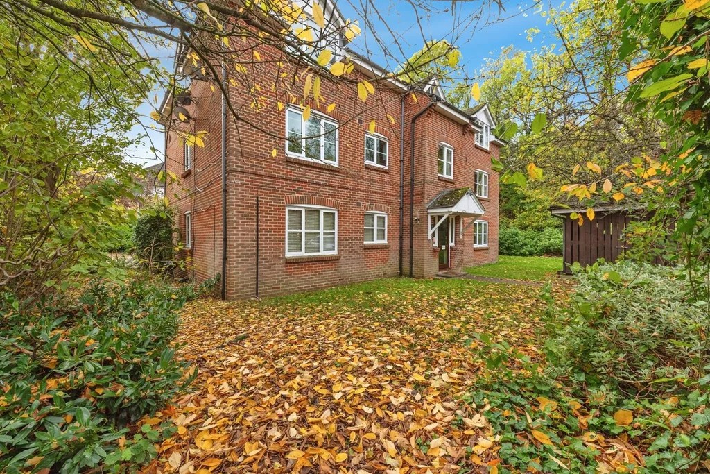 Low-rise red-brick apartment block surrounded by trees